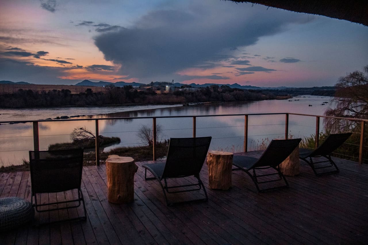A backyard deck at sunset with lounge chairs overlooking the water